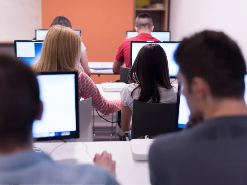 Studenti alle postazioni di un laboratorio di informatica, ripresi da dietro mentre lavorano al computer